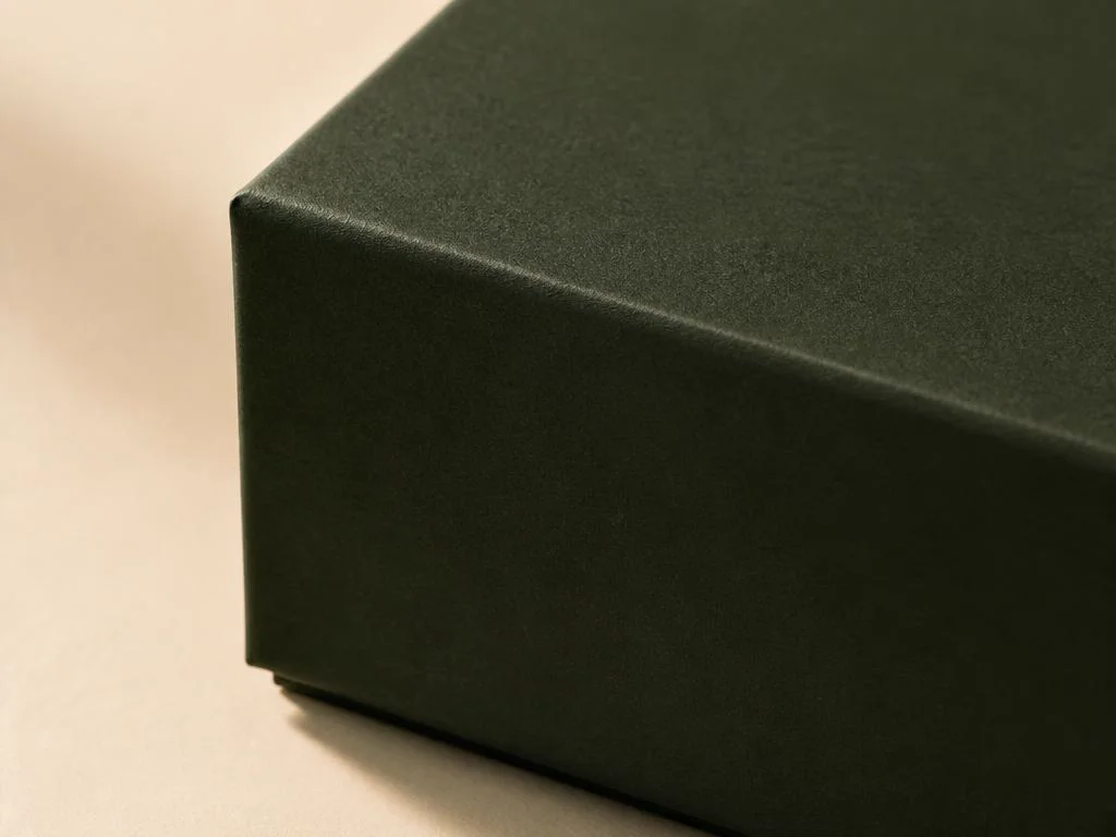 Närbild av en skogsgrön box med sammetslen soft-touch-matt yta